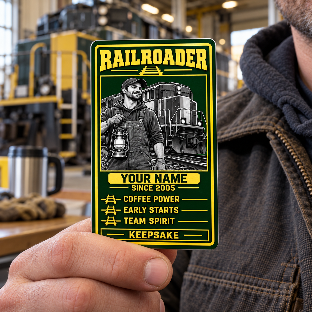 Railroader Trade Legend portrait aluminum keepsake wallet card held by its lower edge in an adult worker's hand at a depot break area.
