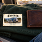 Trucker Ivory Heritage card on folded dark-green work fabric beside a closed wallet