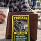 Trucker Trade Legend portrait wallet card against a closed brown wallet on a rest-stop table beside coffee and a parked truck