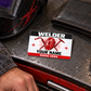 Welder Red Monochrome aluminum wallet card on a toolbox beside a closed wallet and inactive welding hood