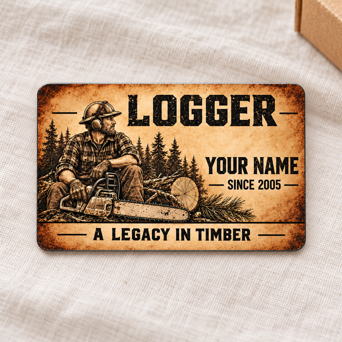 Logger Sepia Legacy aluminum wallet card front on cream linen beside kraft gift box.